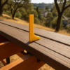 Contractor measuring board gap spacing on a composite deck in an Oakland hills fire zone neighborhood