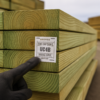 Pressure-treated lumber stack at a Bay Area lumber yard with end-tag use category labels visible on cut board ends