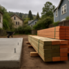 Stacked Douglas fir studs and treated sill plates staged beside a new ADU slab in an East Bay backyard
